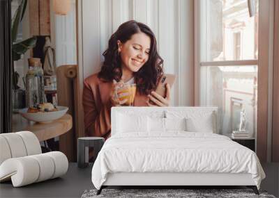 pretty woman in cafe eating and surfing internet on the phone Wall mural