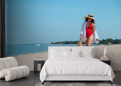 young stunning woman in red swimsuit walking by sea beach Wall mural