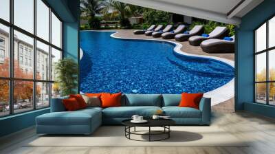 A contemporary resort swimming pool area with clear blue water and comfortable lounge chairs Wall mural