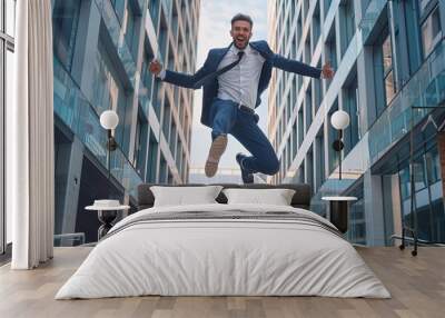 The young businessman happily and confidently jumped between two buildings Wall mural