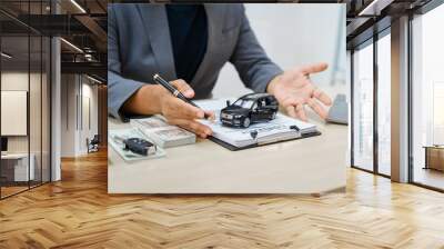 Asian business professional in a formal suit works at a desk, reviewing financial charts. manage car insurance claims, analyze auto loan options, sign lease agreements for vehicle transactions. Wall mural