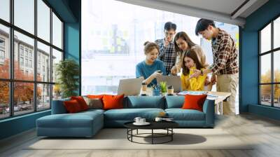 Asian business team working together around a laptop in the meeting room of a modern company. Wall mural