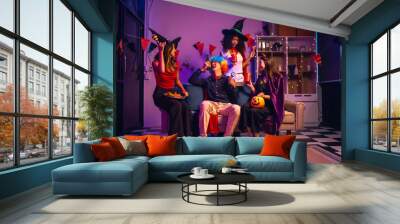 Asian friends, middle-aged man and young woman, enjoy Halloween office party with vampire costumes, fried chicken, grilled food, grape wine, champagne, RGB lights, festive decorations in the night. Wall mural