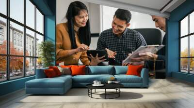 Asian legal team in meeting. woman and two men discussing over documents with law books and gavel on the table, indicating legal setting. Wall mural