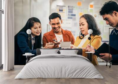 Asian real estate team engaged in a discussion, with two men and a woman focusing on a house model on a table, suggesting a planning or sales meeting. Wall mural