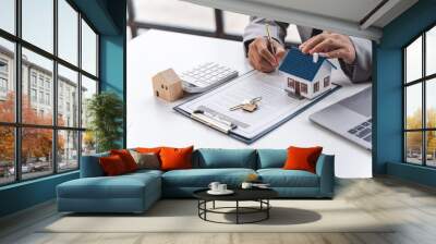 Businessman realtor with house model, sitting at desk, real estate agent manager working on documents, mortgage and property. Wall mural