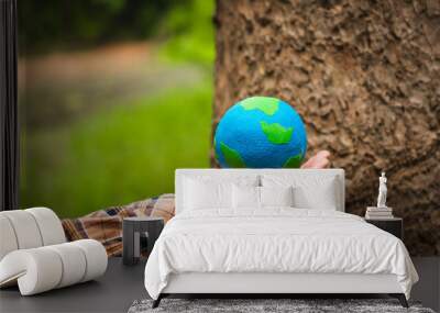 Forest conservationist holds small globe in hands, symbolizing global responsibility for protecting  planet. Standing outdoors in green park, sustainability, commitment to achieving net-zero impact. Wall mural