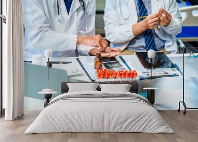 In a hospital meeting room,Italian male and Caucasian male discuss medical cases at desk with X-ray films, blood samples, patient information, on diagnosing heart disease and treatment guidelines. Wall mural