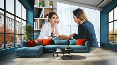 Two Attractive Asian businesswoman who talks with female friend, working in office. Wall mural