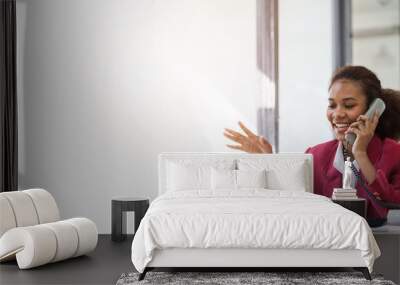 Young african american businesswoman red suit working at desk and using mobile smartphone in the modern office. Call a phone, operator. Wall mural