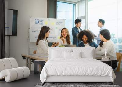 Young and successful mixed race, asian business people working on project together, sitting at table in boardroom. Wall mural