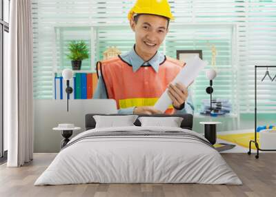 Young Asian man architect working at working desk about his housing project. Wall mural