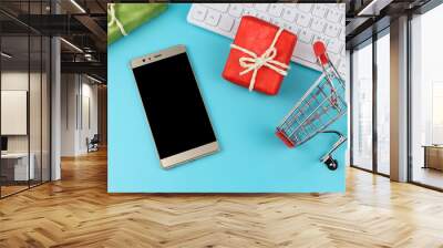 flat lay of mobile phone ,red and green gift boxes with computer keyboard and shopping cart on blue background . Online shopping and Christmas holiday concept. Wall mural