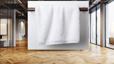 A fluffy white bath towel hanging on a towel rack. Wall mural