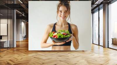 A happy young slim athletic woman in sportswear with salad bowl. White background, diet concept Wall mural