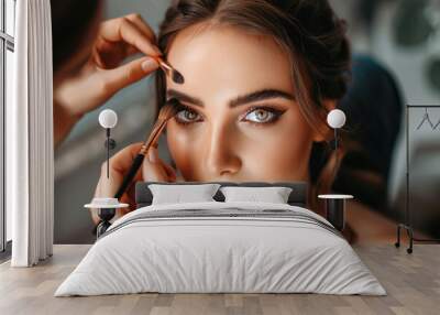 A makeup artist is applying eyeshadow on a young beautiful woman Wall mural