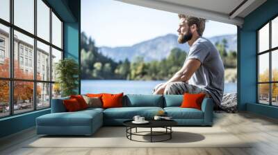 A man sitting on rocks admiring a beautiful lake Wall mural