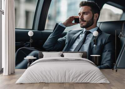 Businessman in a suit is sitting in the back seat of a car and talking on mobile phone Wall mural