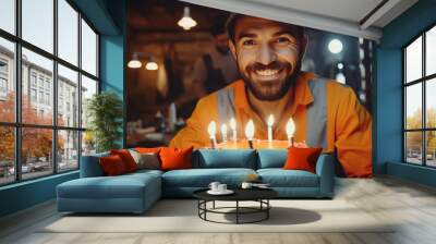 Happy and smiling construction worker with joyful crazy look celebrates his birthday at working place with in front a cake with candles. Generative AI Wall mural