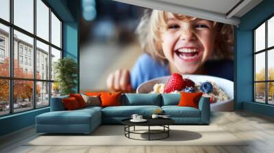 Smiling adorable child having breakfast eating oatmeal porridge with berries.  Wall mural