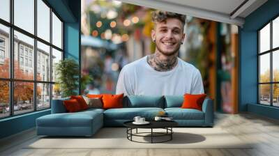 Smiling tattooed young man in casual clothing Wall mural