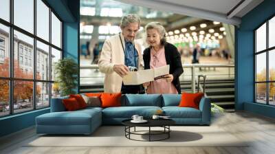 Grandpa and Grandma checking map before travel in international airport Wall mural