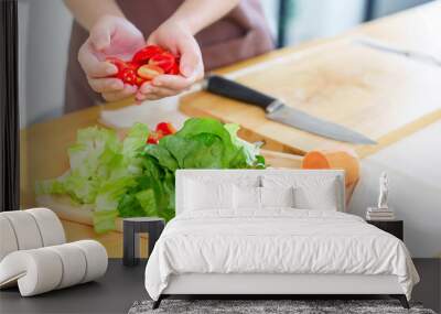 Closeup hands of asian women holding slices tomatoes and slices of fresh vegetables on plate to preparing ingredients for cooking breakfast meal while making healthy food lifestyle in kitchen at home Wall mural