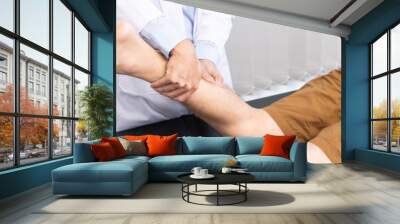 Medical concept a male doctor diagnosing a male patient's leg by pressing his leg because of playing football Wall mural