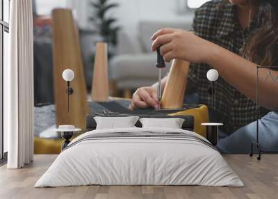 Women use screwdriver equipment to tighten screw while assembling leg of chair to making furniture Wall mural