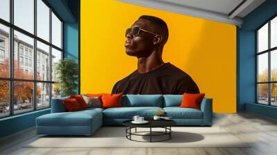 Young black male in black sporty clothes on a bright yellow background Wall mural