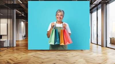 Smiling senior woman holding colorful shopping bags Wall mural