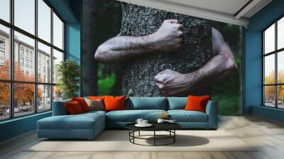 Trunk with human arms. Muscular arms hug a trunk with energy. Conceptual image of contact between man and nature. Suffering of plants and climatic emergency. Wall mural