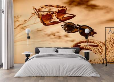 2 pairs of women sunglasses and a bag on a soft orange background and strong shadows of flowers Wall mural