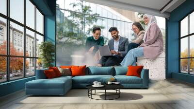 Business colleagues using laptop outside of office building
 Wall mural