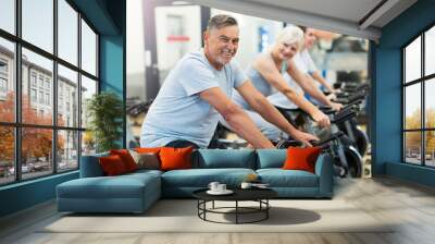 Confident seniors on exercise bikes in spinning class at gym Wall mural