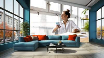 Creative business woman using smartphone in loft office
 Wall mural