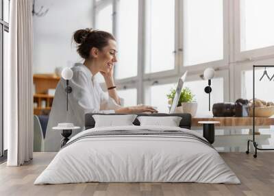 Creative young woman working on laptop in her studio
 Wall mural