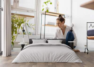 Creative young woman working on laptop in her studio
 Wall mural