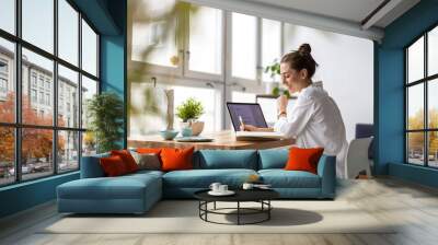 Creative young woman working on laptop in her studio
 Wall mural