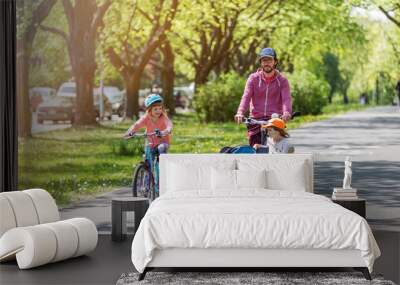 Father and daughters having a ride with cargo bike during spring Wall mural