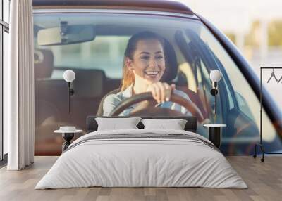 Happy woman driving a car and smiling Wall mural