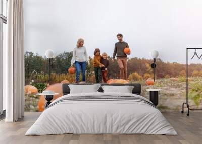 Happy young family in pumpkin patch field Wall mural