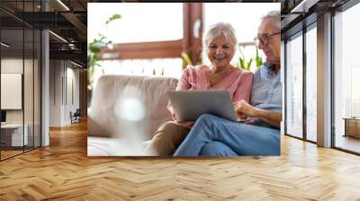 Mature couple using a laptop while relaxing at home Wall mural