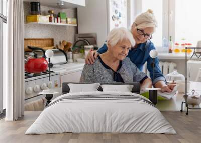 Mature woman helping elderly mother with paperwork
 Wall mural