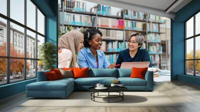 Multiethnic group of students sitting in a library and studying together
 Wall mural