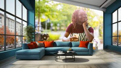 Portrait of a black non-binary person sitting in an outdoor cafe
 Wall mural