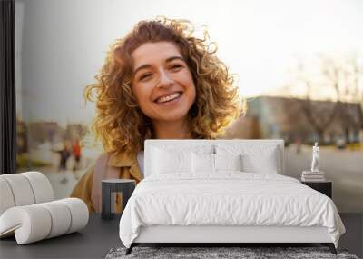 Portrait of young woman with curly hair in the city
 Wall mural