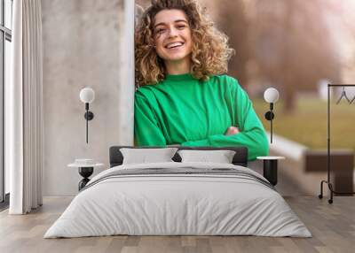 Portrait of young woman with curly hair in the city
 Wall mural