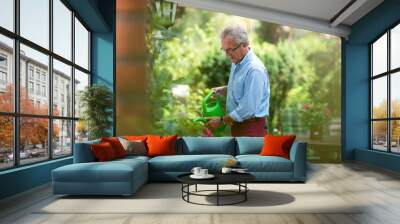 Retired man watering plants in the garden Wall mural