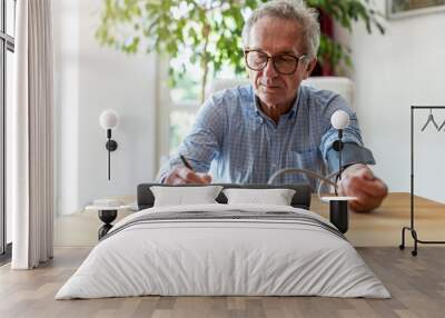 Senior man using medical device to measure blood pressure
 Wall mural